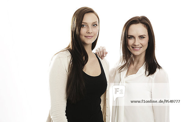 Porträt zweier lächelnder junger Frauen vor weißem Hintergrund