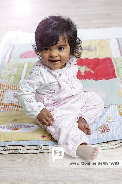 Porträt eines glücklichen Mädchens auf einer Decke sitzend