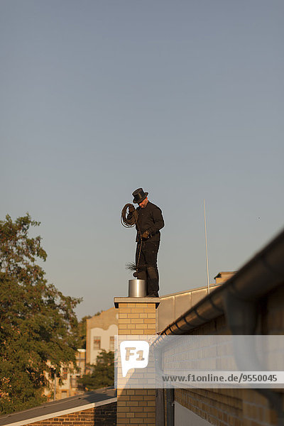 Germany  chimney sweep at work on rooftop