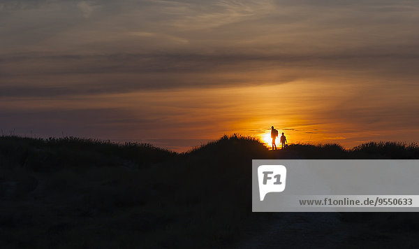 Dänemark  Jütland  Lokken  Mutter und Tochter bei Sonnenuntergang in der Düne wandern