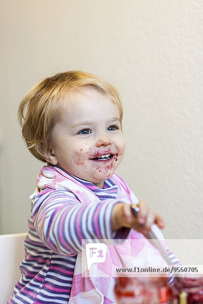 Lächelndes kleines Mädchen mit roter Marmelade bedeckt