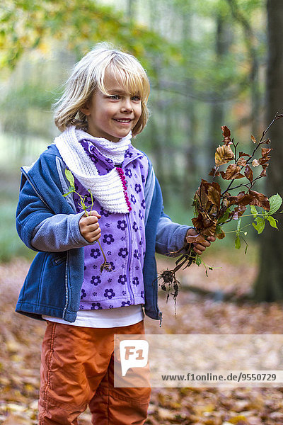 Porträt eines kleinen Mädchens mit Herbstlaub und Pflanzen