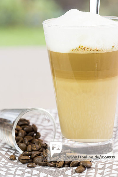 Latte Macchiato und ein Glas Kaffeebohnen auf Tuch