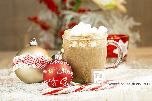 Weihnachtskugeln  Zuckerrohr und Glas heiße Schokolade mit Sahne und Marshmallows auf Kunstschnee