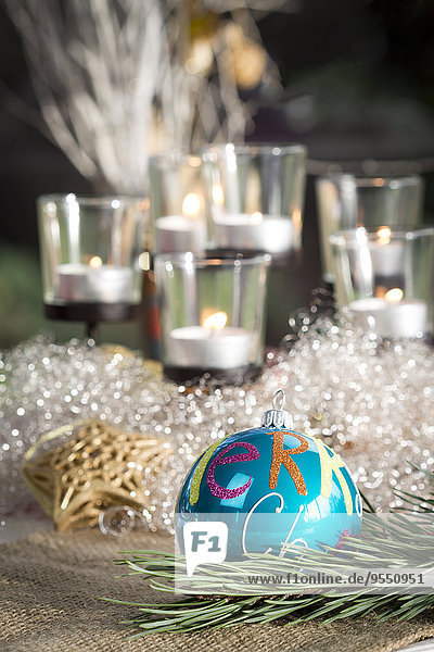 Weihnachtsdekoration  Blaue Weihnachtskugel und Kerzen im Hintergrund