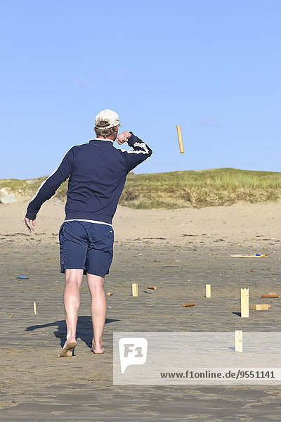 Man playing Kubb on the beach