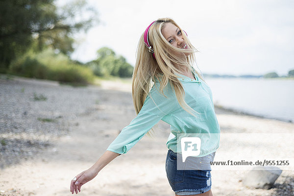 Young woman with headphones dancing on beach