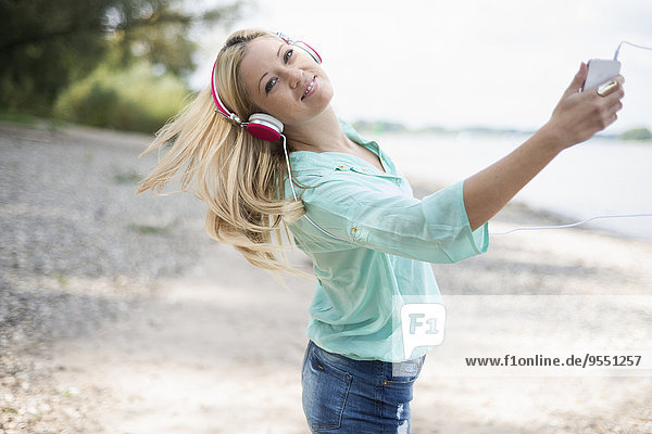 Junge Frau mit Kopfhörer tanzt am Strand