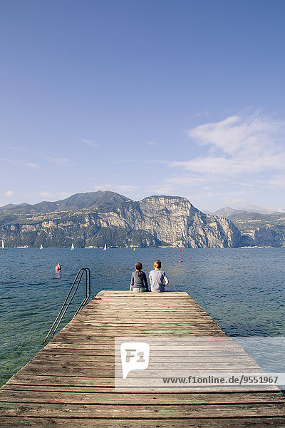 Italy  Veneto  Malcesine  Brothe and sister sitting on jetty