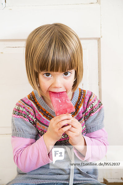Portrait of little girl eating raspberry ice lolly