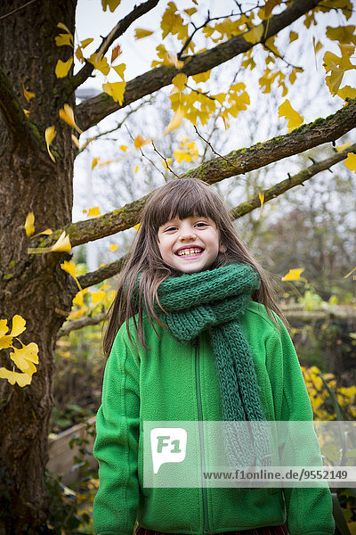 Porträt des grinsenden Mädchens mit grünem Schal und grüner Jacke