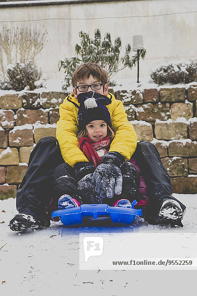 Brother and his little sister sitting on a sledge
