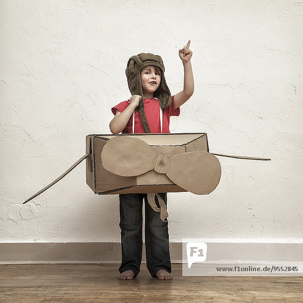 Kleiner Junge spielt mit Pilotenhut und Kartonflugzeug