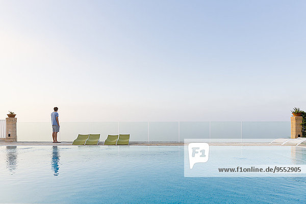 Spanien,  Balearen,  Mallorca,  ein Teenager steht auf einer Glasschiene am Swimmingpool.