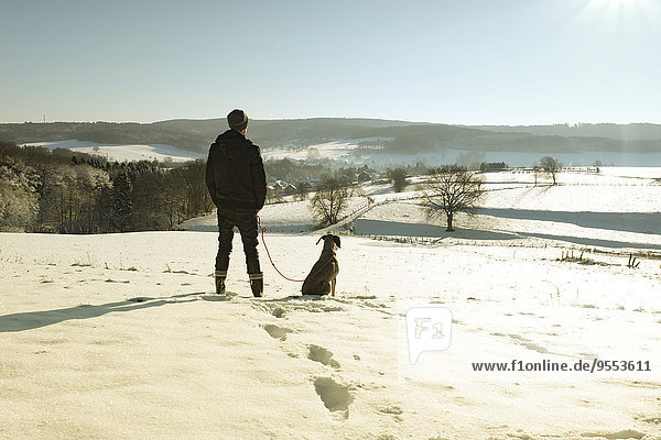 Germany  Bergisches Land  man walking dog in winter landscape