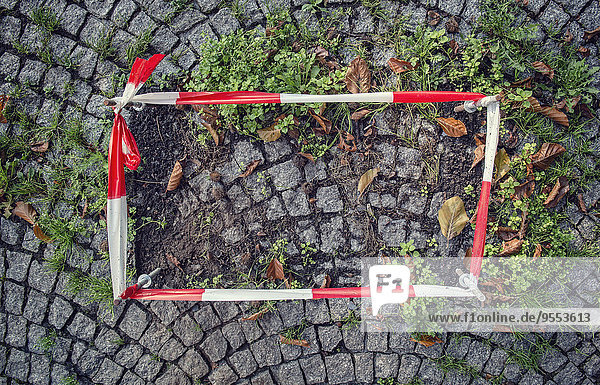 Deutschland,  befestigtes Absperrband um beschädigten Kopfsteinpflasterbelag