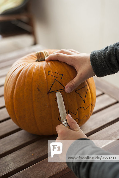 Boy's hands preparing a pumpkin for Halloween lantern