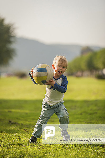 Boy holding ball on meadow