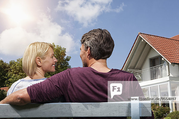 Rear view of mature couple sitting on bench in garden