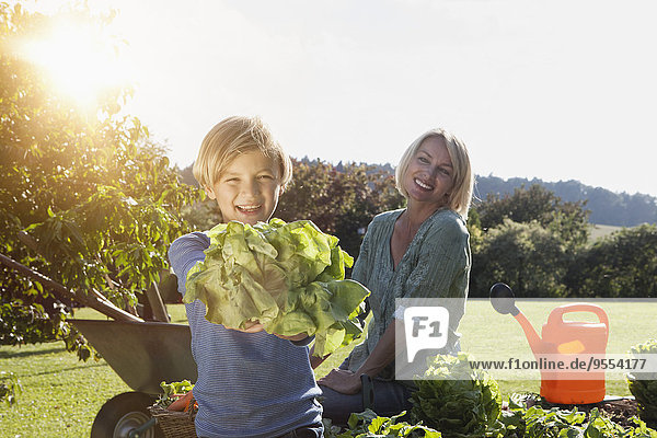 Boy with mother in garden holding salad