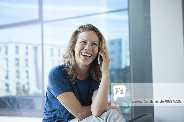Smiling mature woman telephoning with her smartphone at home