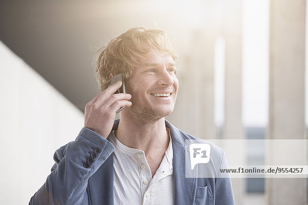 Portrait of smiling man telephoning with smartphone at backlight