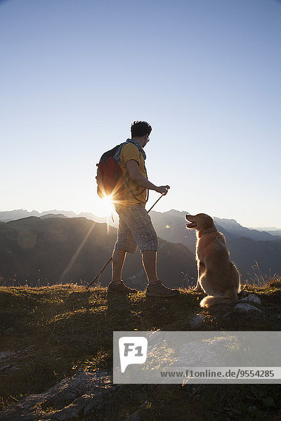 Österreich  Tirol  Unterberghorn  Wanderer mit Hund bei Sonnenaufgang