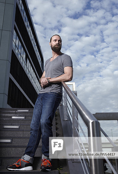 Portrait of man with full beard leaning on railing