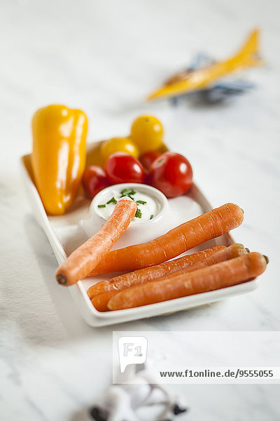 Babygroßes Gemüse  Karotten  Tomaten  Paprika mit Sauerrahmdip  Spielzeugpferd und Hobel  Studio