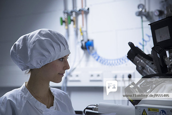 Junge Technikerin beim Betrachten eines Messgerätes in einem Laboratorium