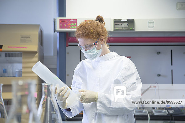 Junge Naturwissenschaftlerin mit Maske im Labor für Biochemie