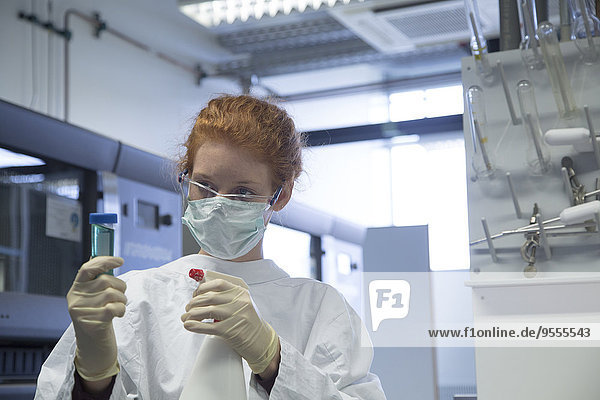 Junge Naturwissenschaftlerin mit Maskendesinfektion im Biochemie-Labor
