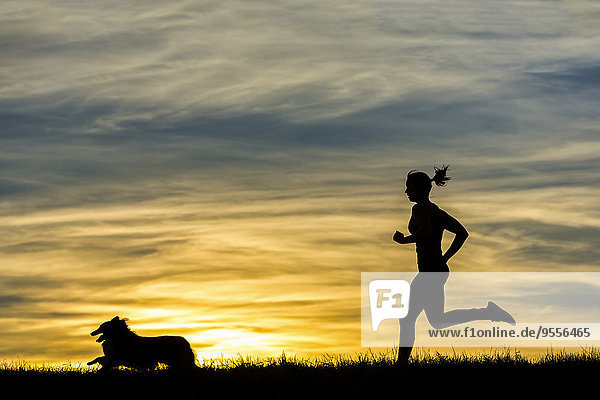 Germany  Female jogger with dog at sunset