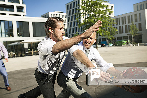 Group of businesspeople playing basketball outdoors