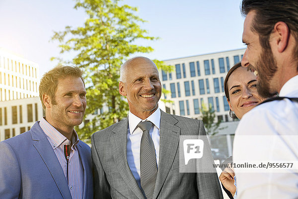 Vier lächelnde Geschäftsleute im Freien