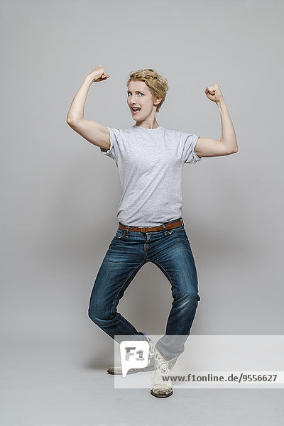 Woman flexing her muscles in front of grey background