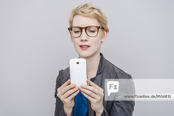 Blonde Frau  die einen Selfie mit ihrem Smartphone nimmt
