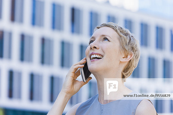 Lächelnde blonde Frau telefoniert mit Smartphone