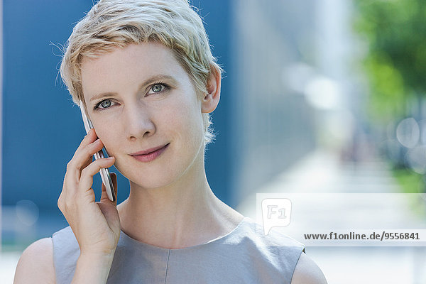 Portrait einer blonden Frau beim Telefonieren mit dem Smartphone