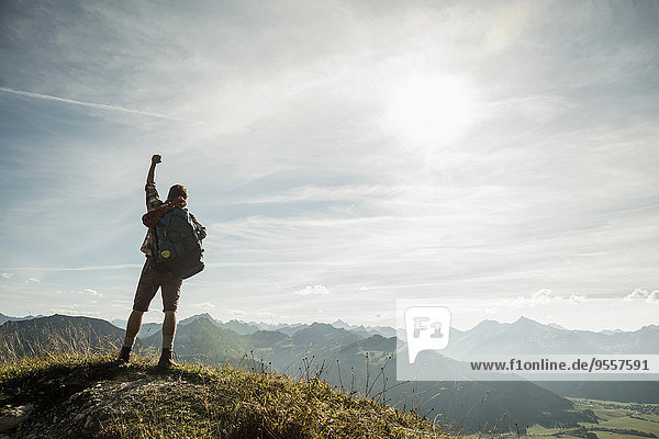 Austria  Tyrol  Tannheimer Tal  young man cheering on mountain top