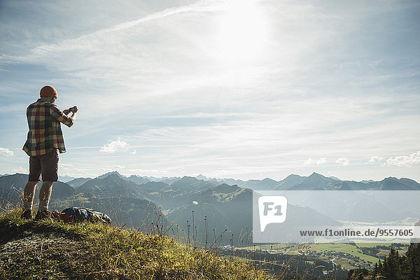 Austria  Tyrol  Tannheimer Tal  young man taking picture in mountainscape