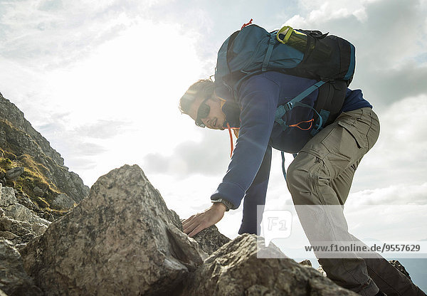 Austria  Tyrol  Tannheimer Tal  young man climbing on rock