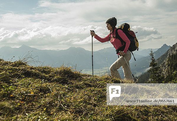 Austria  Tyrol  Tannheimer Tal  young woman hiking on alpine meadow