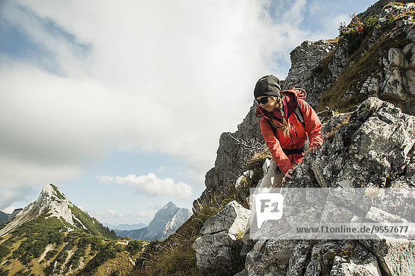 Österreich  Tirol  Tannheimer Tal  junge Frau beim Wandern auf Felsen