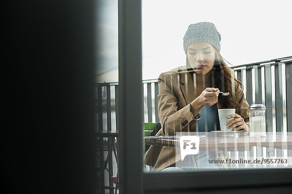 Junge Frau sitzt auf dem Bürgersteig Cafe mit digitalem Tablett