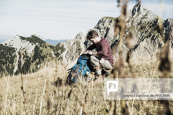 Österreich  Tirol  Tannheimer Tal  junger Mann mit Rucksack auf Alpweide