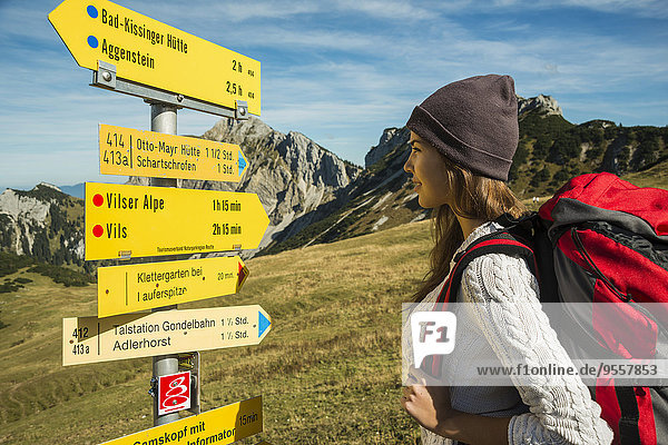Österreich  Tirol  Tannheimer Tal  junge Frau auf Wanderung am Wegweiser