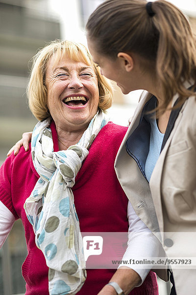 Porträt einer lachenden Seniorin,  die mit ihrer Enkelin kommuniziert.