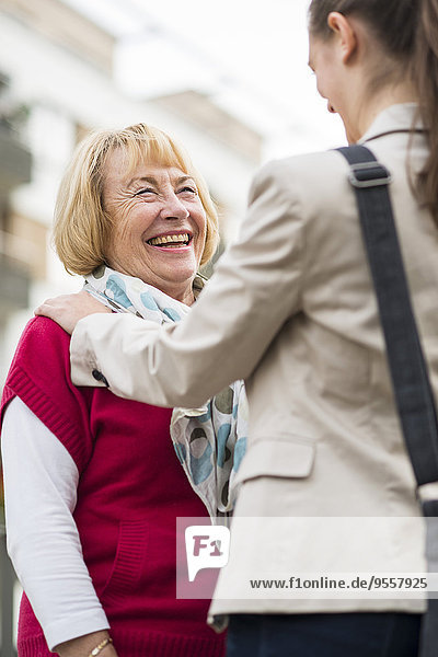 Porträt einer lachenden Seniorin  die mit ihrer Enkelin kommuniziert.