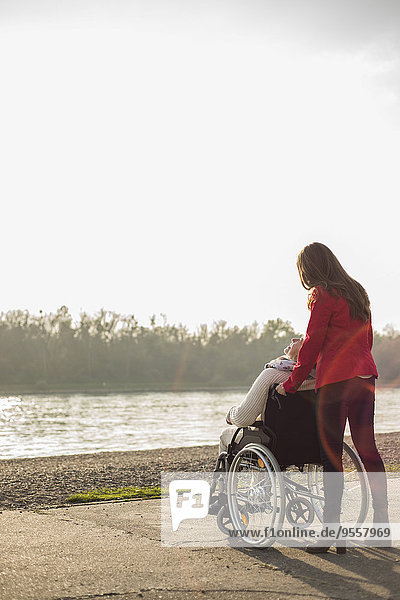 Erwachsene Enkelin  die ihrer Großmutter im Rollstuhl assistiert